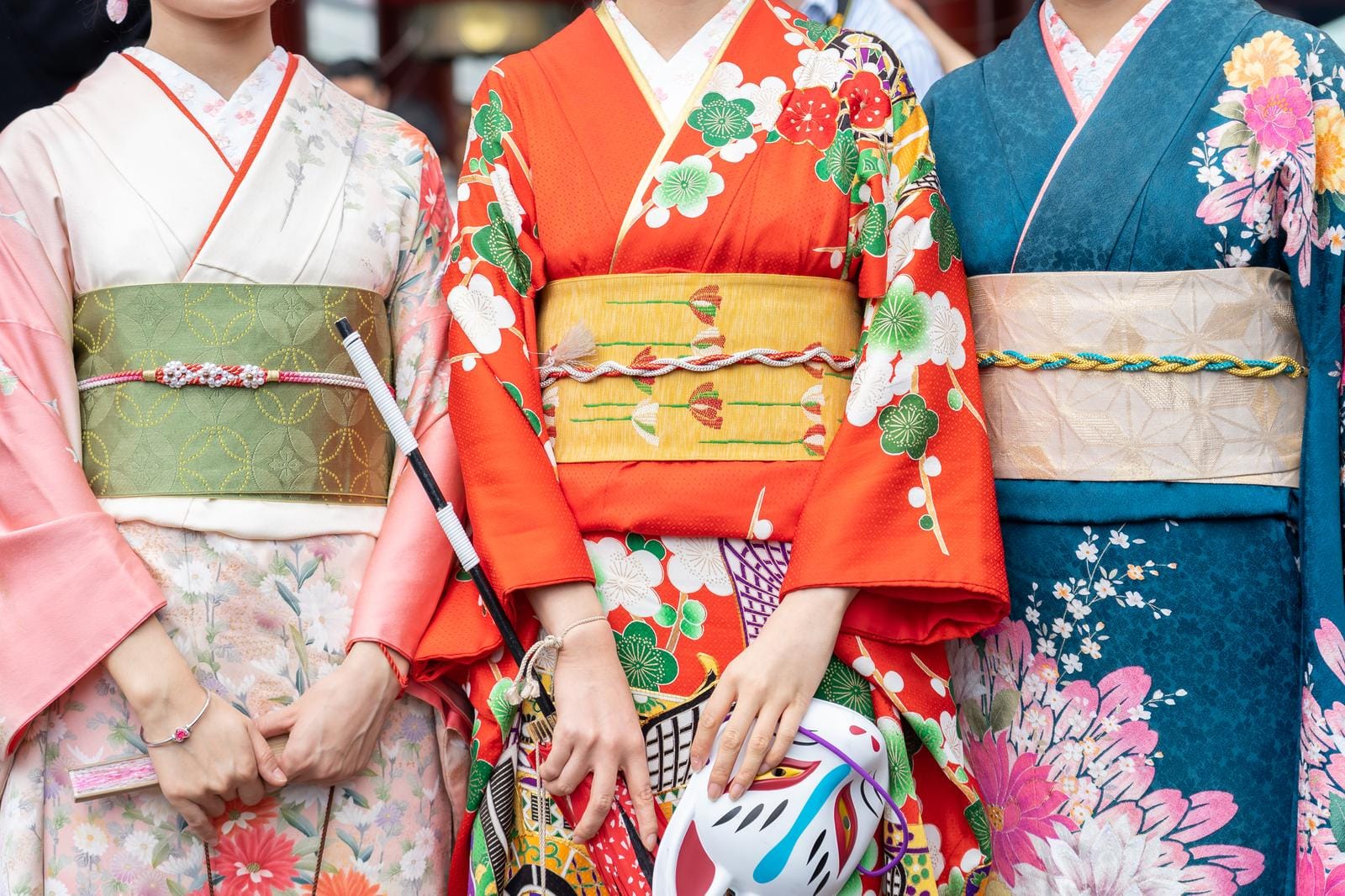 Drei Frauen in traditionellen, farbenfrohen Kimonos mit floralen Mustern in Japan.