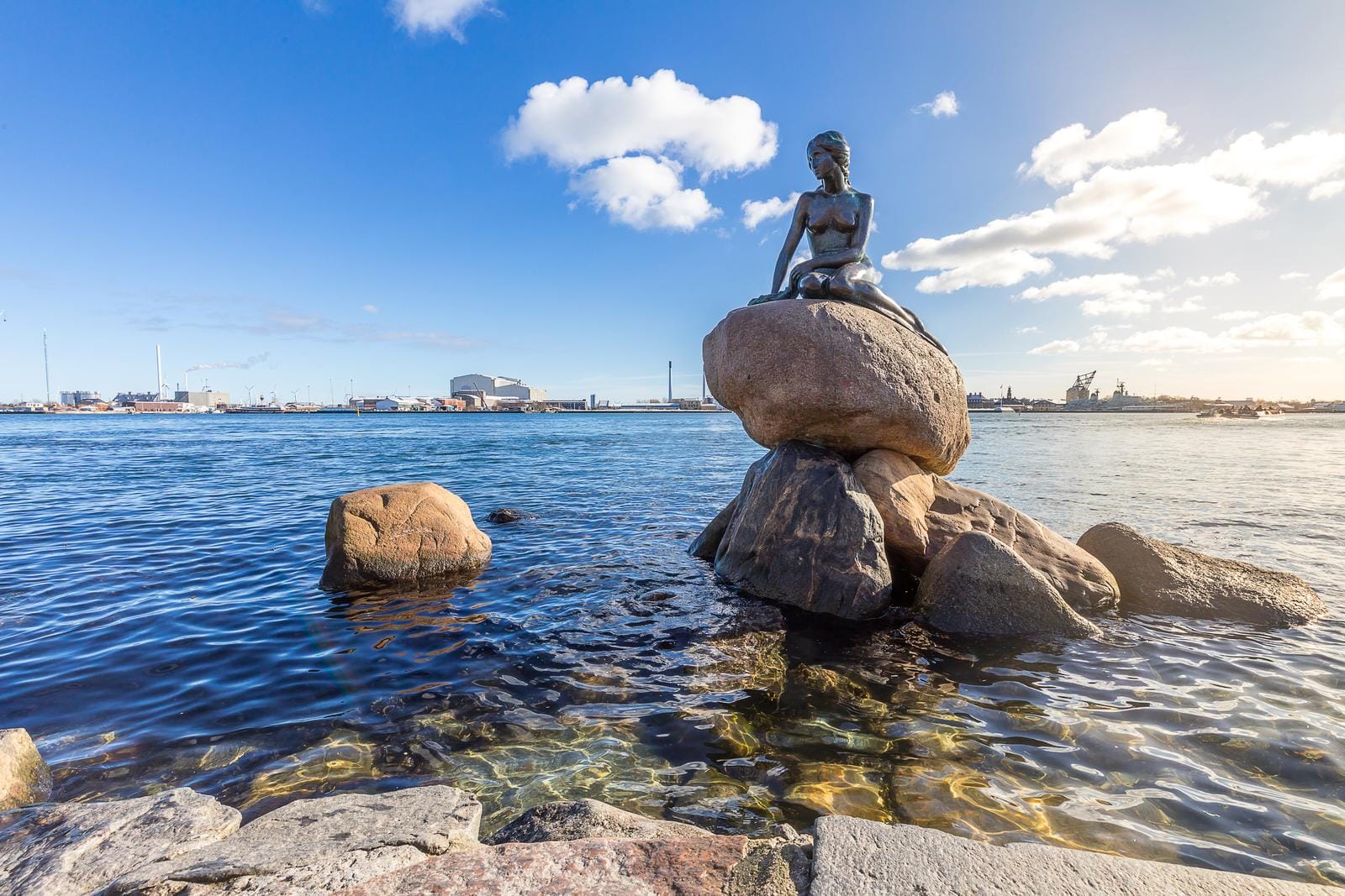 Die Kleine Meerjungfrau-Statue in Kopenhagen, Dänemark, vor blauem Himmel.