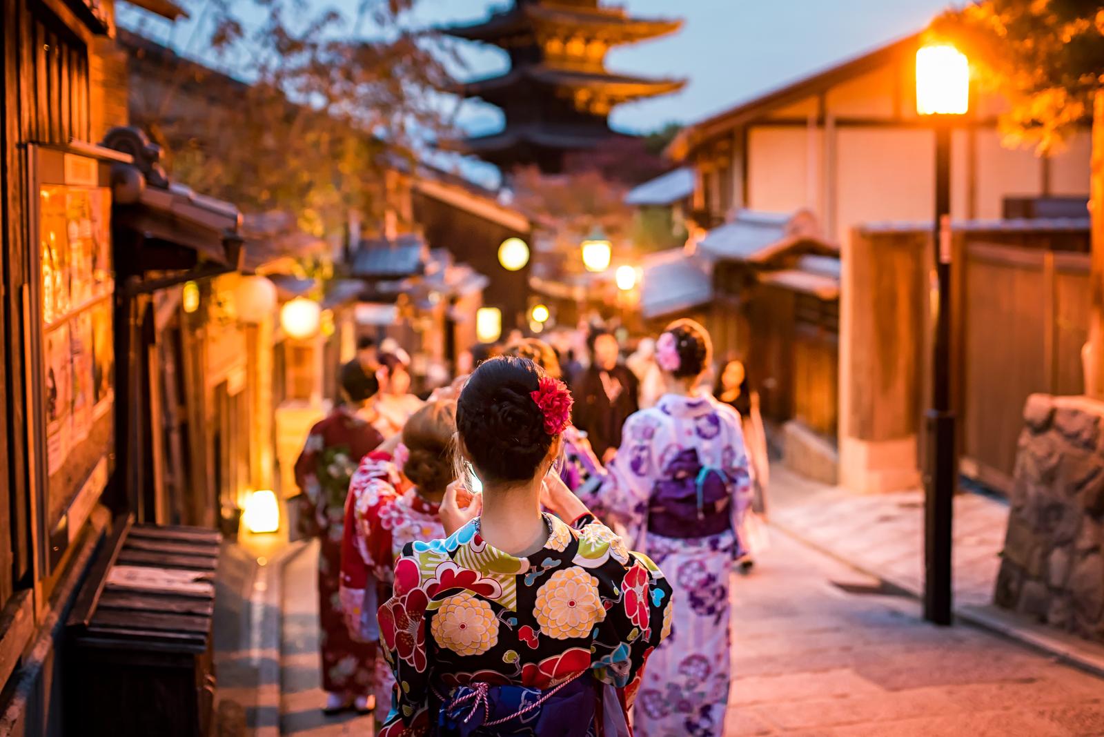 Straße in Kyoto, Japan, mit Frauen in Kimonos bei Abenddämmerung.