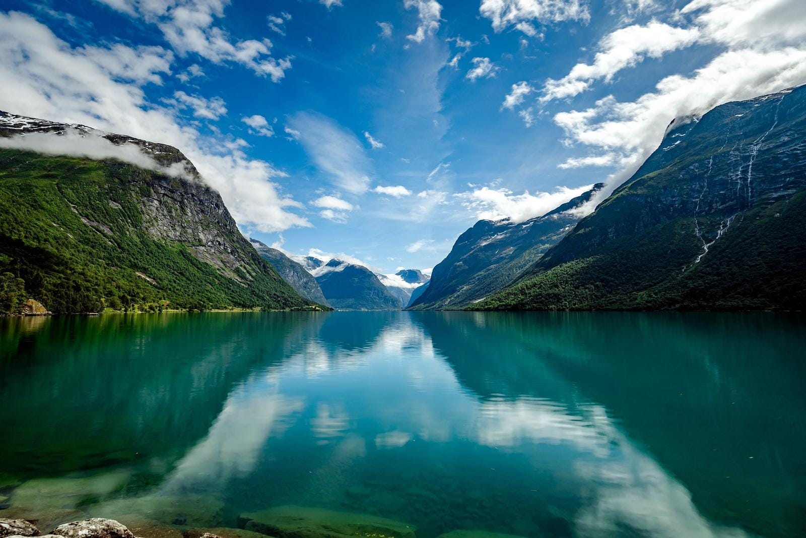 Majestätische Fjordlandschaft in Norwegen mit klarer, spiegelnder Wasseroberfläche und Bergen.