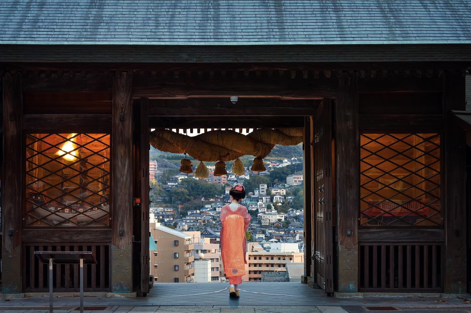 Traditioneller japanischer Torbogen mit Stadtblick, Frau in Kimono im Vordergrund.