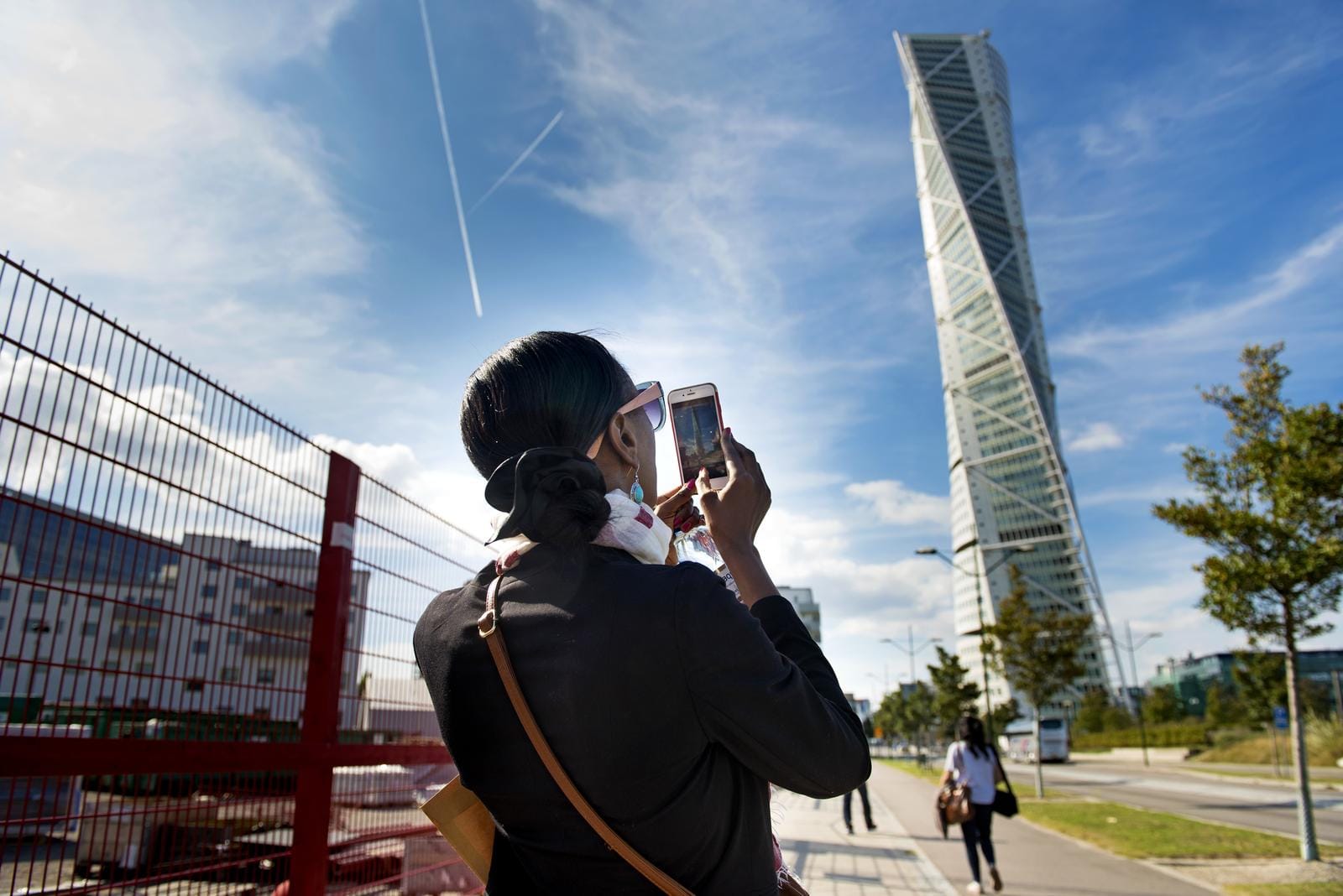 Person fotografiert den Turning Torso in Malmö, Schweden, bei klarem Himmel.