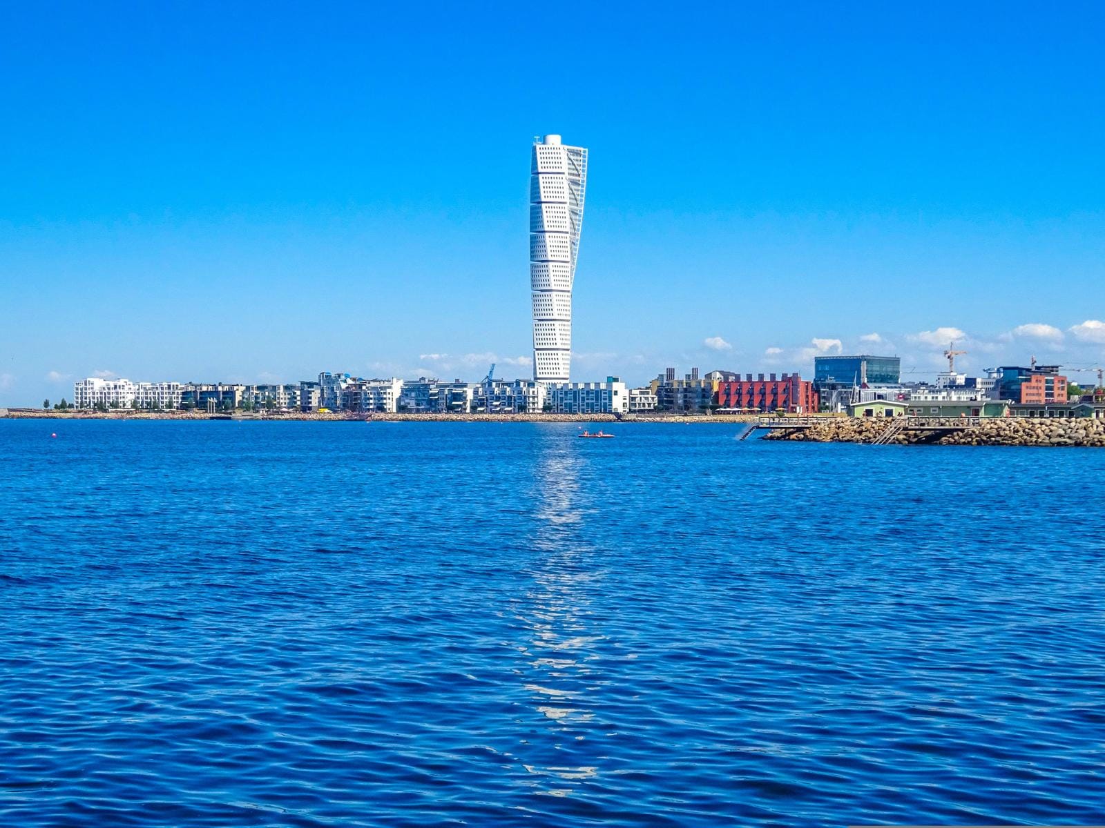 Blick auf Malmö, Schweden mit Turning Torso am blauen Himmel und ruhigem Wasser.