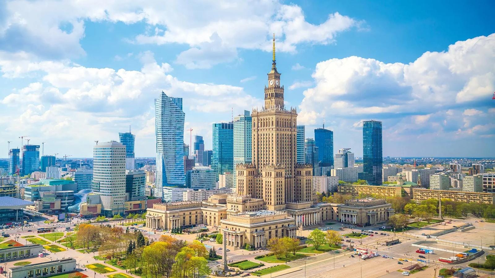 Hochhäuser in Warschau bei strahlend blauem Himmel und moderner Architektur im Kontrast.